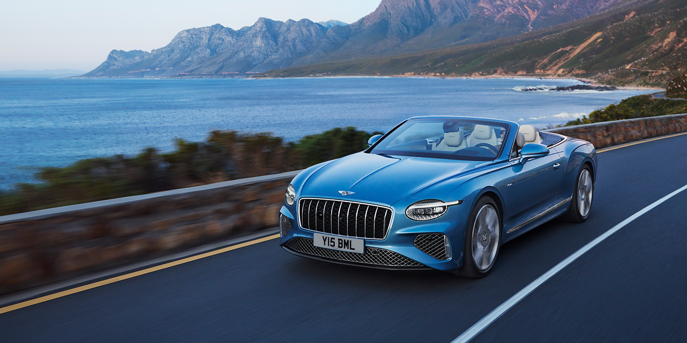 Bentley Baku New Bentley Continental GTC Azure convertible in Light Windsor blue paint with 22 inch Azure wheels and chrome grill, driving dynamically by the sea