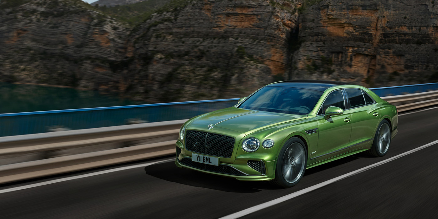 Bentley Baku Bentley New Flying Spur Speed v8 hybrid sedan driving dynamically on a mountain road in Tourmaline Green paint
