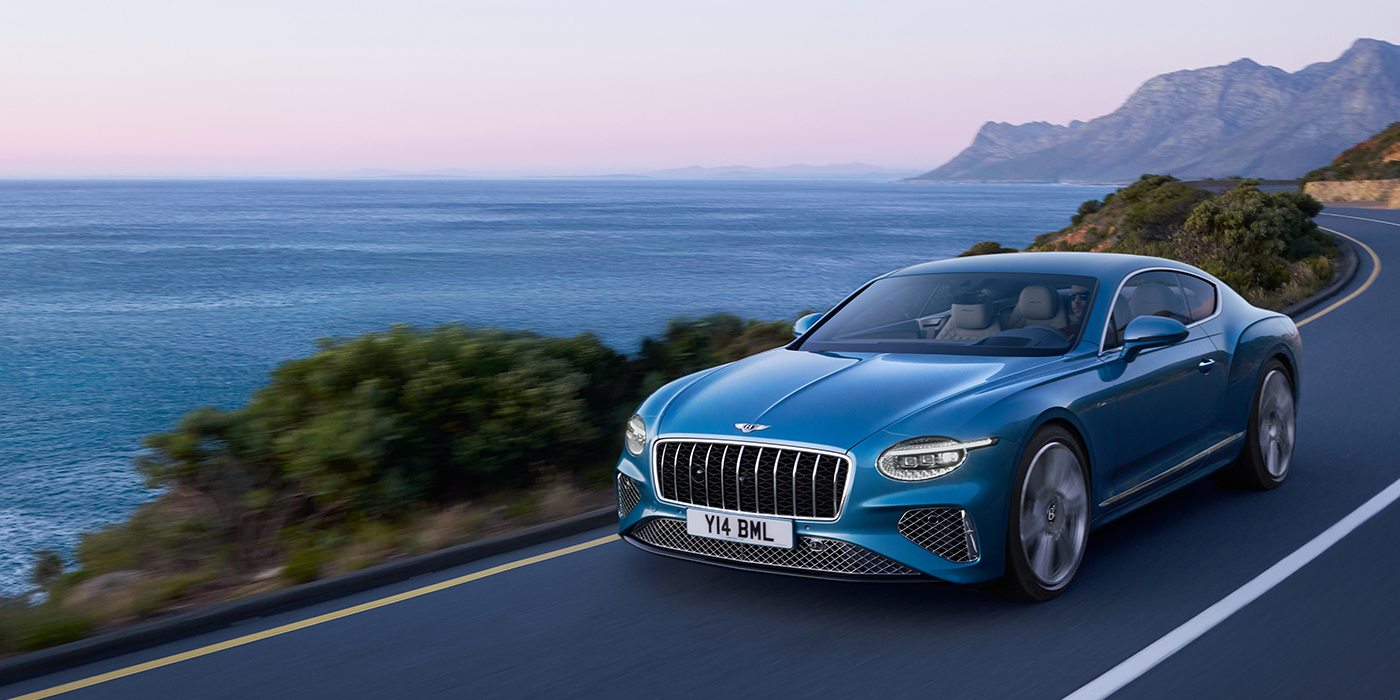 Bentley Baku New Bentley Continental GT Azure coupe in Light Windsor blue paint with 22 inch Azure wheels and chrome grill, driving dynamically by the sea