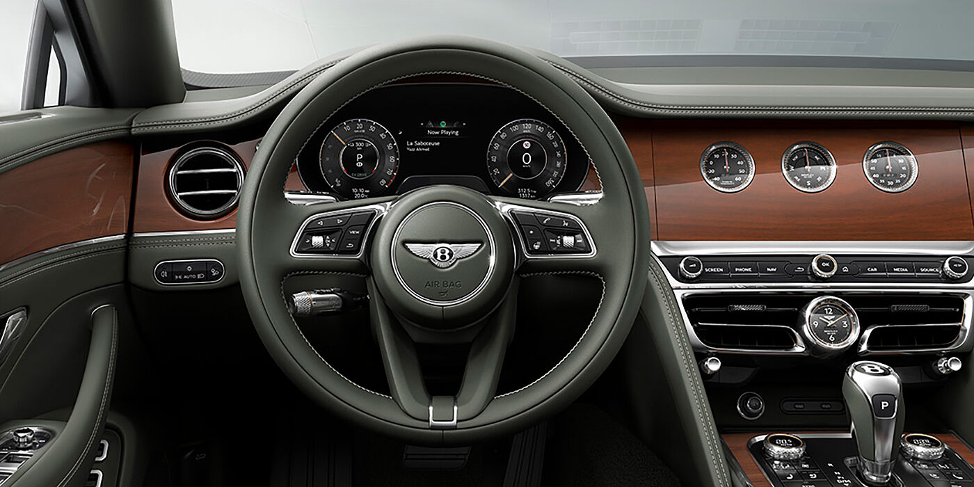 Bentley Baku New Bentley Flying Spur sedan front cabin in Cumbrian Green hide and Crown Cut walnut veneer showing steering wheel and Rotating Display with three clocks on face