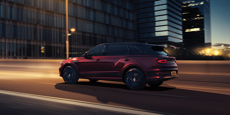 Bentley Baku Bentley Bentayga Extended Wheelbase Mulliner SUV in Cricket Ball red paint driving dynamically in city at night